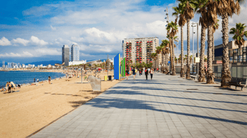 Paseo marítimo de la Barceloneta en Barcelona con vistas al mar Mediterráneo, palmeras y ambiente local junto a la playa.