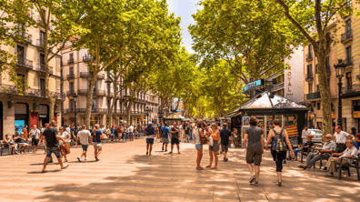 Imagen de Las Ramblas de Barcelona con gente paseando, terrazas animadas y el icónico mosaico de Miró en el suelo.