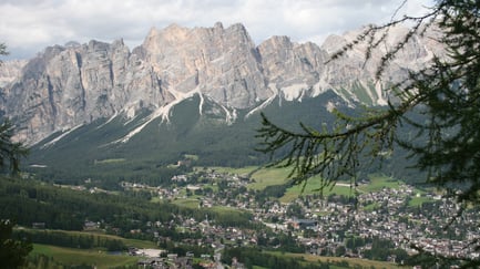 Vista panorámica de Cortina d’Ampezzo con montañas dolomíticas, valle verde y el pueblo integrado en el paisaje alpino.