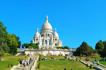 Basílica del Sacré Coeur en lo alto de Montmartre, París, con escaleras y visitantes disfrutando de la vista