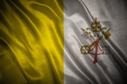 Bandera del Vaticano amarilla y blanca con el escudo papal, ondeando en tela.