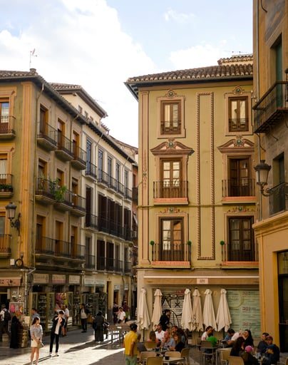 Terraza de bar en una calle del centro de Granada, con edificios históricos de colores y balcones.