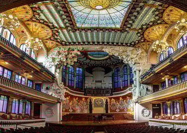 Interior del Palau de la Música Catalana en Barcelona, con vitrales coloridos, detalles modernistas y su espectacular claraboya central.