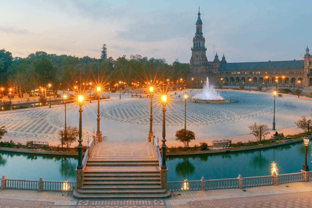 Imagen panorámica desde una perspectiva aérea de la Plaza de España de Sevilla, al atardecer, con las farolas encendidas