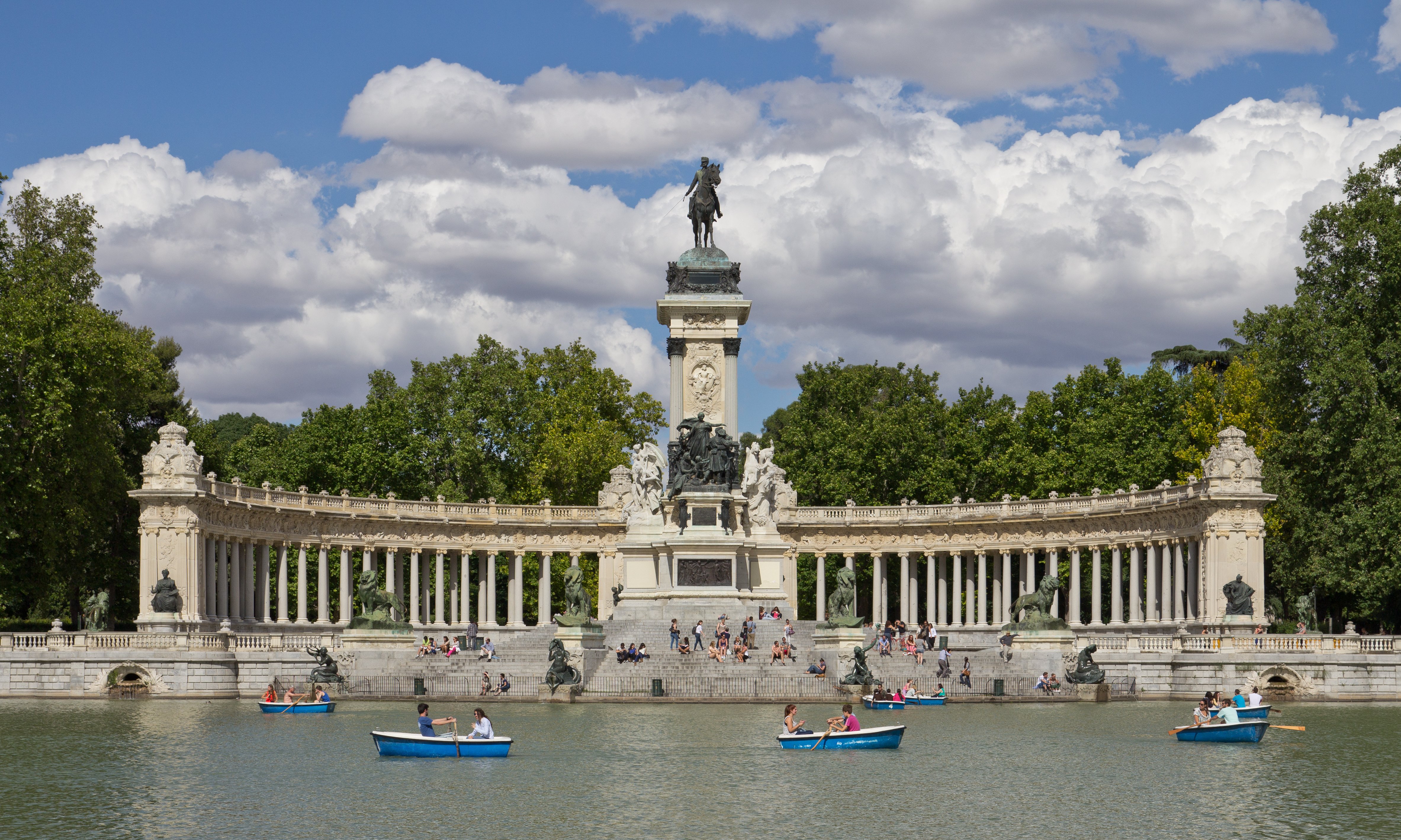 Imagen panorámica del estanque central del Parque del Retiro con personas remando en barca