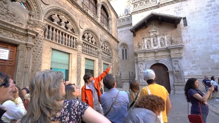 Guía turístico explicando la historia de la Capilla Real de Granada a un grupo de visitantes frente a su fachada renacentista.