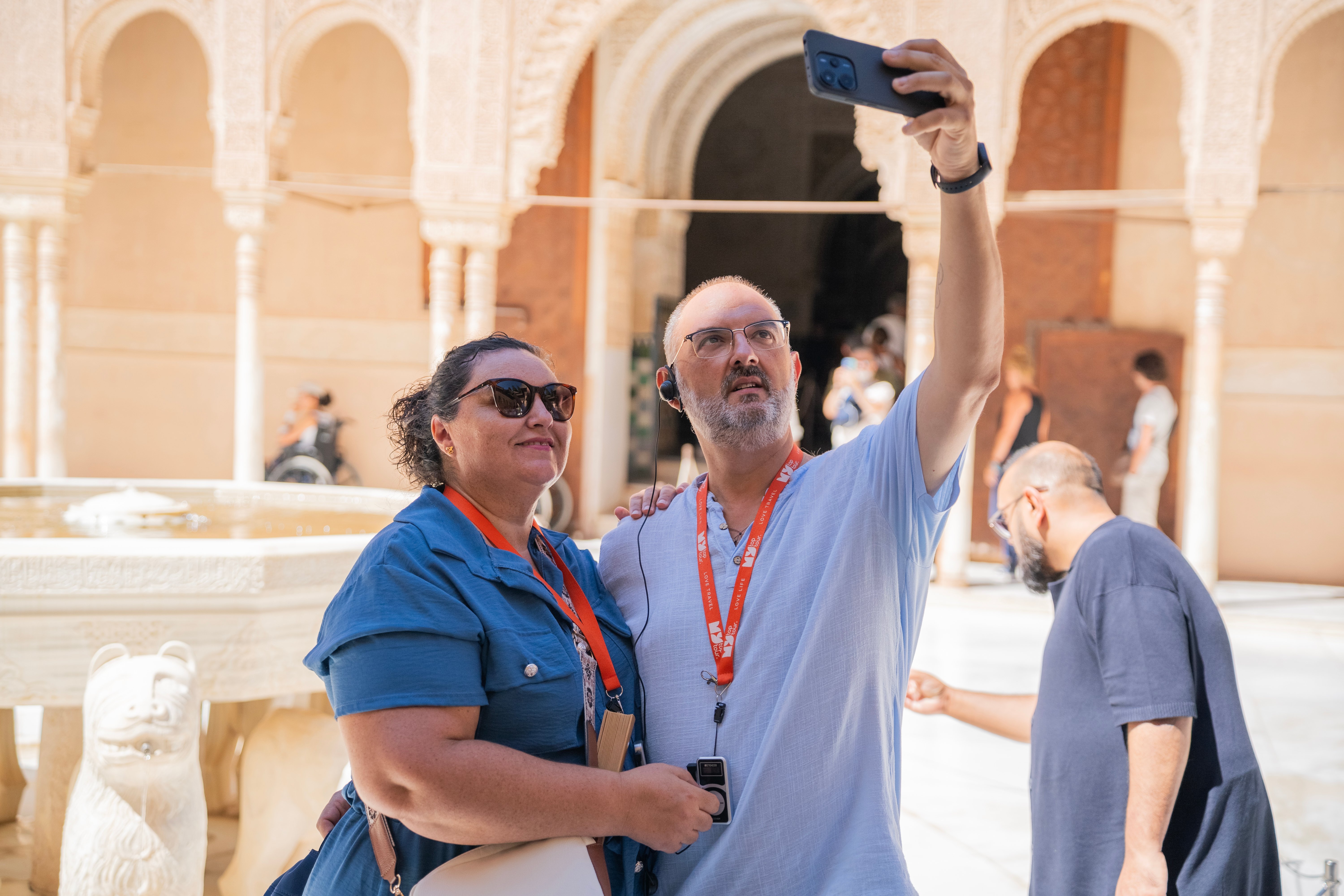 Dos viajeros se fotografían junto a la Fuente de los Leones de la Alhambra